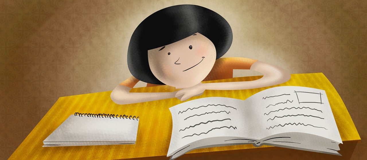 Uśmiechnięte dziecko siedzące przy biurku przed otwartą książką i notatnikiem.